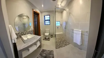 a bathroom with a shower and a sink and a mirror at Kiewiets Nest in Victory Hill