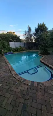 a swimming pool in a yard with a brick driveway at Kiewiets Nest in Victory Hill