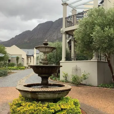 a fountain in front of a building with a mountain at Apartment Franschhoek 121 Lermitage in Franschhoek