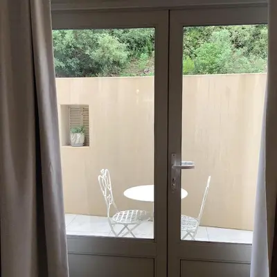 a glass door with two chairs and a table at Apartment Franschhoek 121 Lermitage in Franschhoek