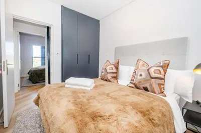 a bedroom with a large bed with a brown blanket at Paarl 225 - Lux Modern 2 Bedroom Apartment with Parking in Paarl