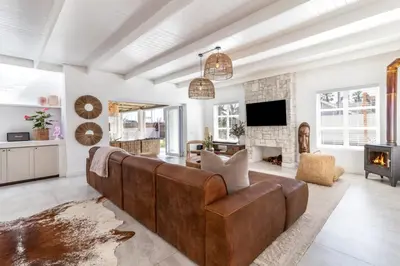 a living room with a brown couch and a fireplace at Luxury Flamingo Villa at beach with Pool and Solar Back Up in Cape Town