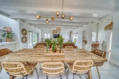 a dining room with a large wooden table and chairs at Luxury Flamingo Villa at beach with Pool and Solar Back Up in Cape Town