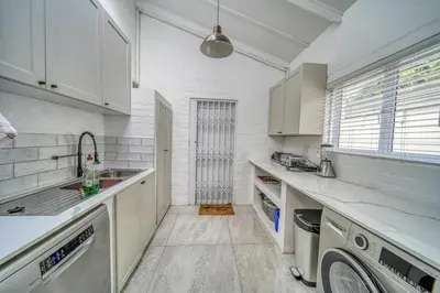 a kitchen with white cabinets and a washer and dryer at Luxury Flamingo Villa at beach with Pool and Solar Back Up in Cape Town