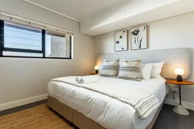 a bedroom with a large white bed and a window at Waters Edge Apartments by Propr in Cape Town