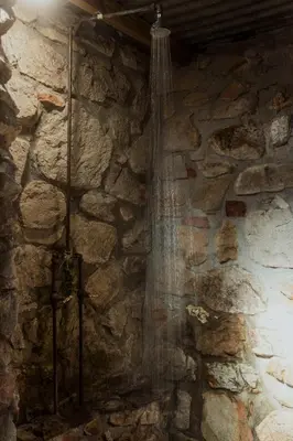 a shower in a room with a stone wall at Glen Oakes Farm Stay in Hartebeest Rivier
