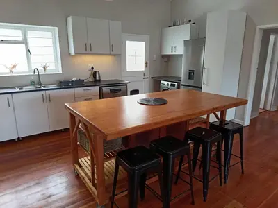 a kitchen with a wooden table and stools at Rockwest 1 Cosy summer holiday house Hermanus in Hermanus