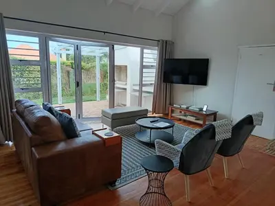 a living room with a brown leather couch and chairs at Rockwest 1 Cosy summer holiday house Hermanus in Hermanus
