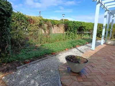 a garden with a pot of plants on a brick walkway at Rockwest 1 Cosy summer holiday house Hermanus in Hermanus