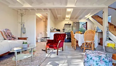 a living room with red chairs and a table at Beach House, Pool, Braai, Patio, Water Sports in Hermanus
