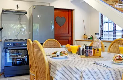 a kitchen with a table with chairs and a table with food on it at Beach House, Pool, Braai, Patio, Water Sports in Hermanus