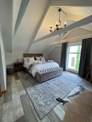 a bedroom with a large bed and a chandelier at Stay At Nantes in Paarl