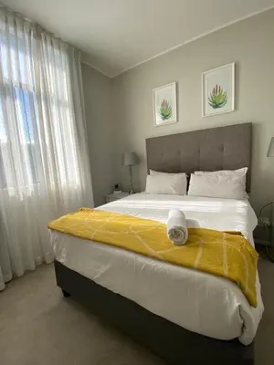 a bedroom with a large bed with a yellow blanket at Serene Global Capetown Axis in Cape Town