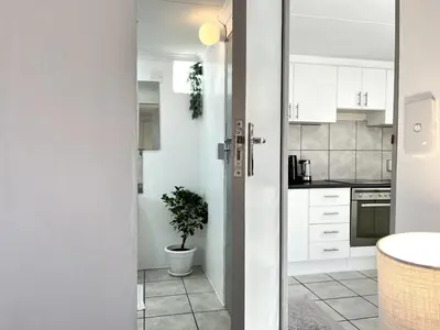 a kitchen with white cabinets and a potted plant at Cosy Flatlet in Chrismar in Stikland
