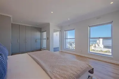 a bedroom with a large bed with a large window at Breakwater Nr 4 holiday apartment in Hermanus