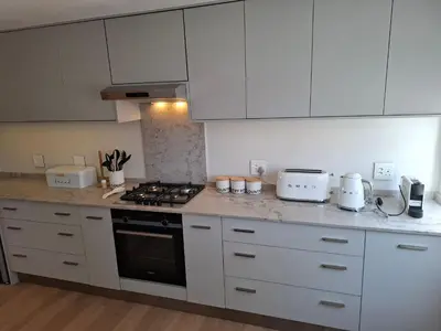 a kitchen with white cabinets and a stove top oven at Breakwater Nr 4 holiday apartment in Hermanus