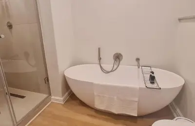 a bath tub in a bathroom with a shower at Breakwater Nr 4 holiday apartment in Hermanus