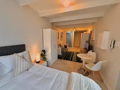 a bedroom with a bed and a table and a room at Secure & Central, Modern Flatlet in Cape Town