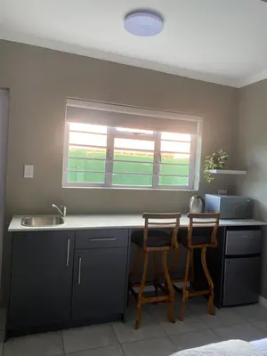 a kitchen with two chairs at a counter with a window at The Perfect Spot in Welgelegen