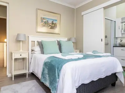 a bedroom with a large bed with blue and white sheets at Mountain Rest Hermanus in Hermanus