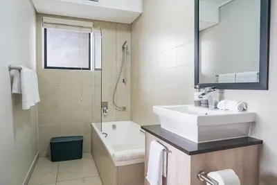 a bathroom with a sink and a tub and a toilet at Walk to Canal Walk - Modern Flat in Cape Town