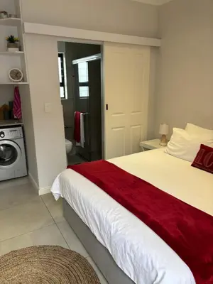 a bedroom with a large bed with a red blanket at Studio Apartment in Cape Town in Cape Town