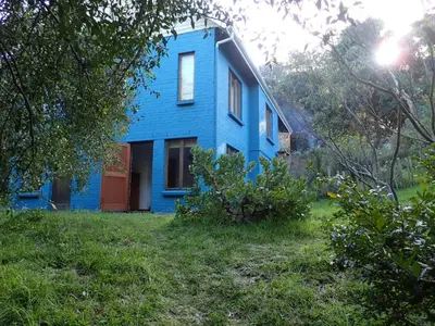 a blue house with a red door in a yard at Yellowwood Place in Bettyʼs Bay