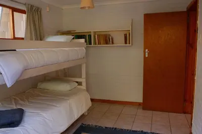 a bedroom with two bunk beds and a door at Yellowwood Place in Bettyʼs Bay