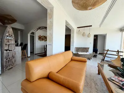 a living room with a brown couch and a table at Kiwara at C, Gordon's Bay in Gordonʼs Bay