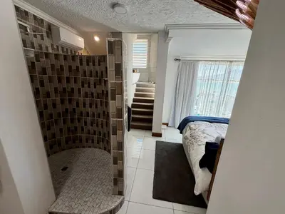 a bedroom with a shower and a bed in it at Kiwara at C, Gordon's Bay in Gordonʼs Bay