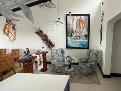 a living room with chairs and a painting on the wall at Kiwara at C, Gordon's Bay in Gordonʼs Bay