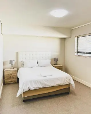 a bedroom with a large white bed and two night stands at Modern One Bedroom Apartment Next to Canal Walk Mall in Cape Town