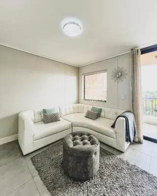 a living room with a couch and a table at Modern One Bedroom Apartment Next to Canal Walk Mall in Cape Town
