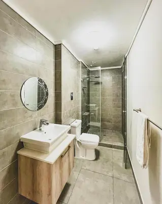 a bathroom with a sink and a toilet and a shower at Modern One Bedroom Apartment Next to Canal Walk Mall in Cape Town