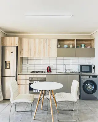 a kitchen with a table and two chairs and a sink at Modern One Bedroom Apartment Next to Canal Walk Mall in Cape Town