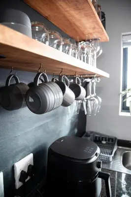 a bunch of cups hanging on a shelf in a kitchen at Apartment Paradys 2 - Serviced in Stellenbosch