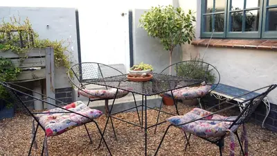 a patio table with four chairs and a pot on it at The Art Room in Somerset West