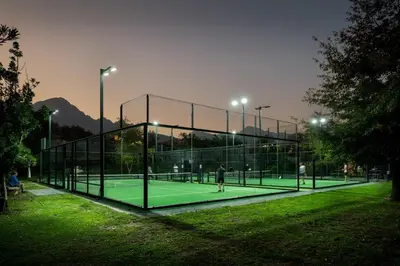 two people playing tennis on a tennis court at night at The Art Room in Somerset West