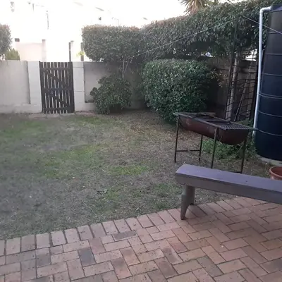 a bench in a yard with a fence and a grill at Cozy Corner in Cape Town