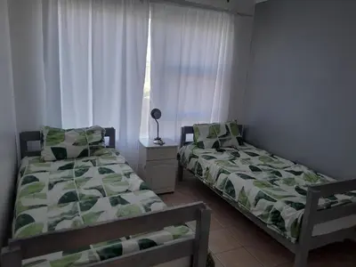 two beds in a small room with a window at Cozy Corner in Cape Town