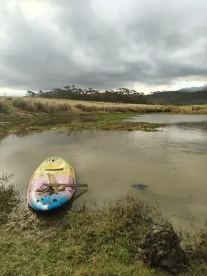 a small boat sitting on the shore of a river at Cabin on Spinlea Farm Campsite in Caledon