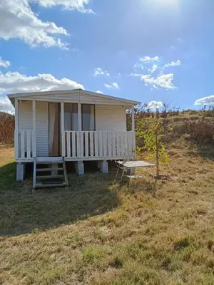 a small white house with a porch in a field at Cabin on Spinlea Farm Campsite in Caledon