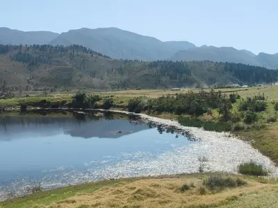 a lake in a field with mountains in the background at Cabin on Spinlea Farm Campsite in Caledon