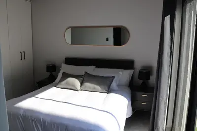 a bedroom with a white bed with a mirror on the wall at 21b on SANDOWN in Cape Town