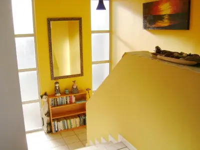 a yellow room with a mirror and a book shelf at Aandvari Sunset Court in Cape Town