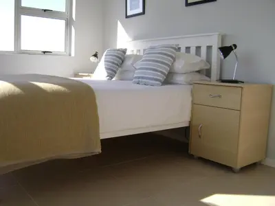a bedroom with a white bed with blue and white pillows at Aandvari Sunset Court in Cape Town