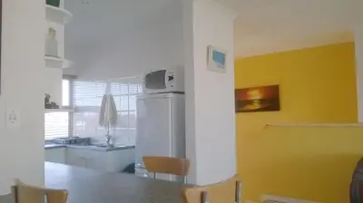 a kitchen with a refrigerator and a table with chairs at Aandvari Sunset Court in Cape Town