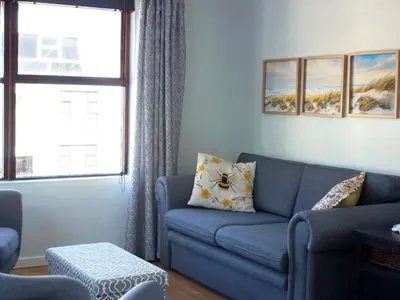 a living room with a blue couch and a window at Sea Urchin in Gordonʼs Bay