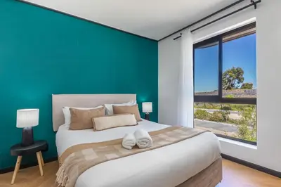 a bedroom with a large bed with a blue wall at Nine Palms - Century City Luxury Apartment in Cape Town