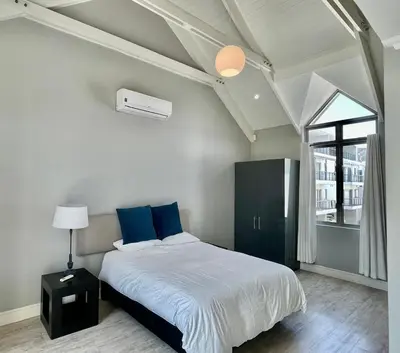 a bedroom with a bed with blue pillows and a window at Franschhoek Gem on Van Wijk in Franschhoek